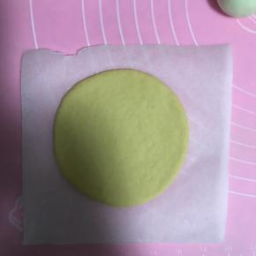 11.取一个黄色面团，垫油纸，均匀擀薄，直径13厘米左右