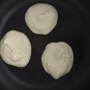 8.将平底锅放在灶台上，开微火，将面糊用勺舀至锅中，我是放入一勺后再叠加一勺，这样松饼有厚重感，吃起来还有点q弹的感觉！盖上锅盖，一定要最小火，大概一分钟左右关火，不要掀锅盖，闷两分钟钟左右翻面！翻面时间自己掌握，因为厚，如果翻面过早，很易碎！