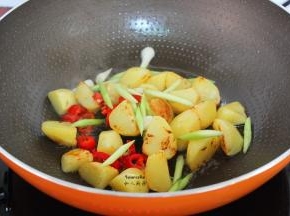锅中再油，把土豆煎炸熟，放入蒜白、辣椒；