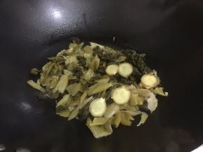 5. 码入姜片和酸菜翻炒