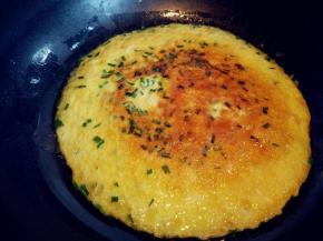 待底部凝固，将另一平底不粘锅烧热，扣在这个锅上，迅速翻转，就可以将蛋饼和香肠完整地翻面