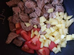 将洋葱、牛肉和西红柿放入电压力锅中，将一小半土豆切小块放入（另一半留着切大块之后放）