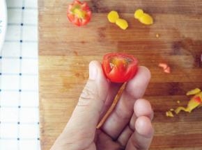 将圣女果洗净，横向对半切开，用小刀如图刻出花瓣，完成后备用