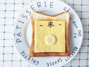 另一片烤好的吐司片，上面放一块早餐奶酪，切一块香蕉放在中间，再用巧克力画出余下的部分即可。