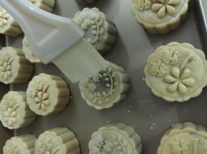 14. 定形好拿出刷上蛋液，刷蛋液用毛刷轻轻刷上去，毛刷上有多余的蛋液就在碗边刮掉多余的蛋液这样刷出来的月饼纹路才够清晰