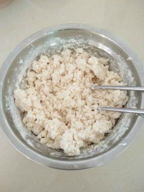 把面粉、盐倒入碗中混合，加入热水，用筷子挑成絮状。