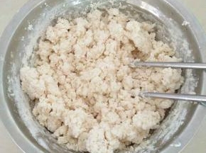 把面粉、盐倒入碗中混合，加入热水，用筷子挑成絮状。