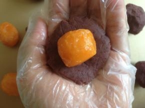 豆沙馅压扁一下，放入整个蛋黄