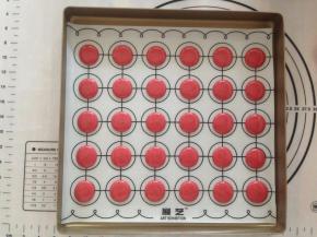 在马卡龙垫上垂直挤出圆形，挤好后，将烤盘从离台面十多公分处垂直向下震出气泡