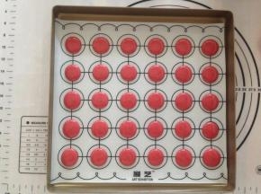 在马卡龙垫上垂直挤出圆形，挤好后，将烤盘从离台面十多公分处垂直向下震出气泡