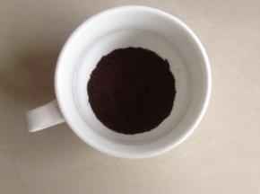 先在杯子底部勺一些饼干粉末，用勺子压紧