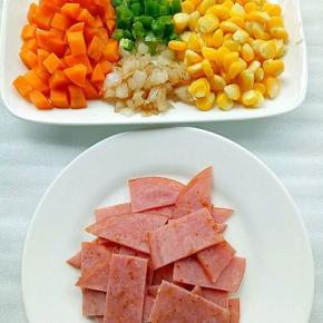 胡萝卜粒，玉米粒提前焯水，火腿片不放油放锅中煎至两面微黄切块，青椒粒，洋葱粒放入锅中炒片刻