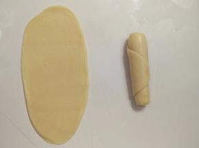 包好的面团收口朝上，用擀面杖擀成椭圆形，由下往上卷一起，这样就完成了第一次擀卷，全部面团都这样操作。