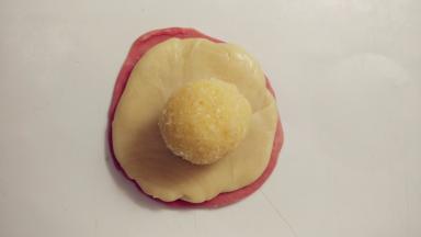 再取一个红色面卷同样操作。接着在红色的面饼上放上白色的面饼，再放上椰蓉馅。
