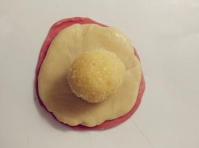 再取一个红色面卷同样操作。接着在红色的面饼上放上白色的面饼，再放上椰蓉馅。