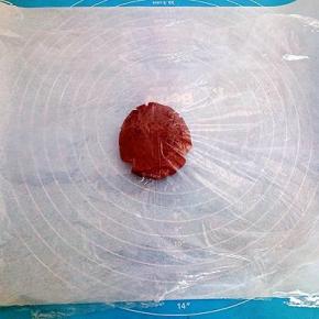 取一张和烤盘差不多大的油纸垫在下面（在准备1张油纸备用）取一块面团放在上面，盖一层保鲜膜