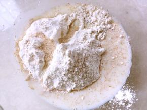 高筋面粉加全麦面粉加一小撮盐，酵母跟砂糖，加牛奶用筷子搅拌成棉絮状