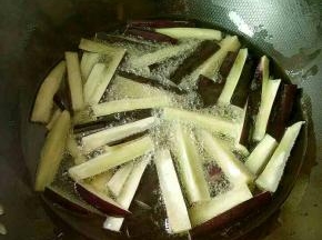 热锅倒油，烧至5成热，下长茄炸至表面微黄，捞出控油。