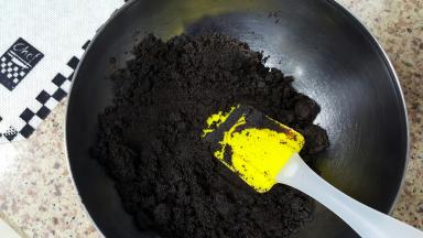 3．将融化后的黄油，倒入巧克力饼干末中进行混合。