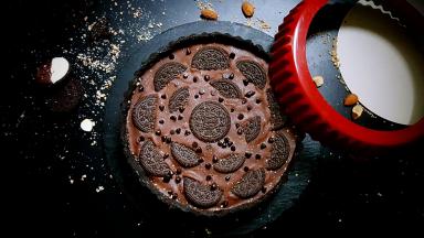 13．开始组合，将巧克力甘纳许倒在香蕉片上，奥力奥饼干斜插在上面，再撒上耐热巧克力豆，就完成了。放在冰箱中冷藏最好过夜。