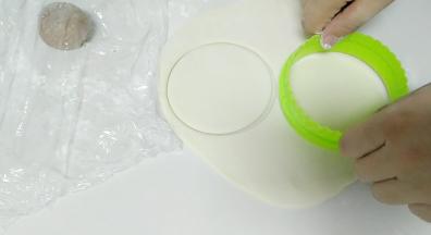 面团发好，揉捏排气，然后取出圆形的包子皮。