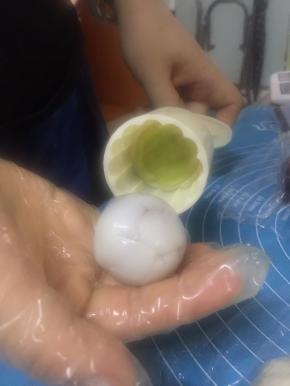 揪一点抹茶的，和白的皮共20克，在模具上粘上熟粉，把抹茶先按上面，余下的白色面团包上馅放入模具