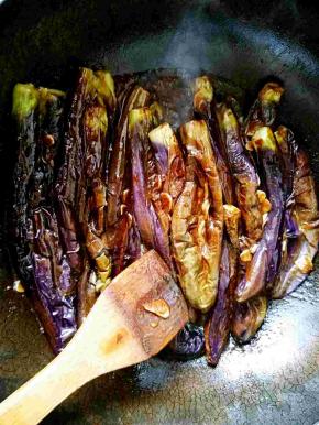 用木铲按压搅拌，确保每一个茄子都裹上酱汁，方便入味。