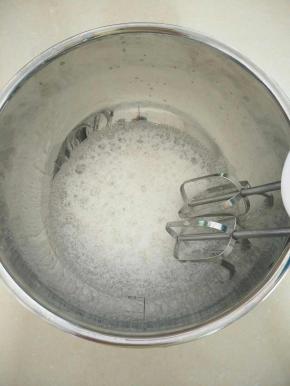 把蛋白和白醋倒入碗中，用打蛋器打出大气泡，加入一半的白糖。