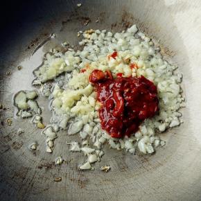 锅中放油，六成热时开小火放入蒜蓉和豆瓣酱炒香。