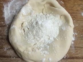 醒发好的面团做成一个碗状，里面放干面粉