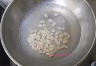 炒锅里倒入一碗水烧热，水冒小泡时，倒入腌好的鸡肉粒，用筷子将鸡肉粒搅散开，待鸡肉粒变色后捞出；