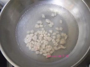 炒锅里倒入一碗水烧热，水冒小泡时，倒入腌好的鸡肉粒，用筷子将鸡肉粒搅散开，待鸡肉粒变色后捞出；