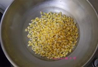 炒锅里再另倒入一碗水，倒入玉米粒，开火，煮至玉米粒变色；