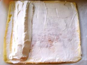 将奶油抹在蛋糕上，靠近卷起的一边多一些