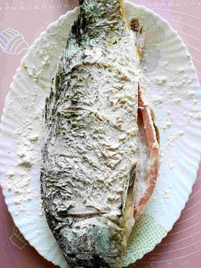 把鱼通体涂满面粉，抖去多余的浮粉，放置片刻，目的是让面粉更好的吸附在鱼身上，方便一会儿煎制。