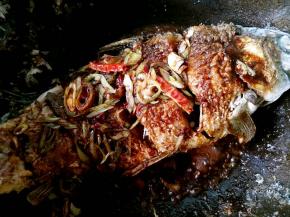 把汤汁浇在鱼身上，然后把鱼推回锅的中心。