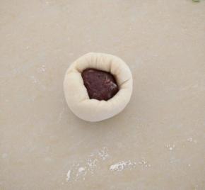 白色面团按扁，放上15克的豆沙，收口。