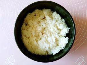 把米饭铺在石锅中，用饭铲按压平整。