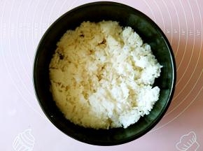 把米饭铺在石锅中，用饭铲按压平整。