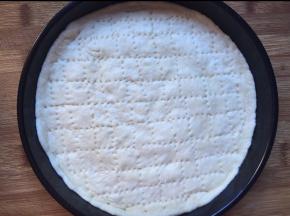 饼底用擀面棒擀成圆形，放入披萨盘，用叉子叉上洞，避免烤的时候饼底膨胀太高