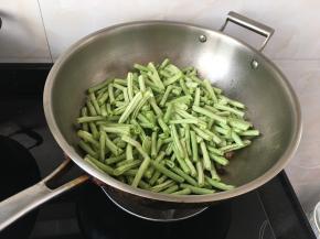 加入豇豆一起翻炒两分钟，注意火候不要烧糊了，多加些油