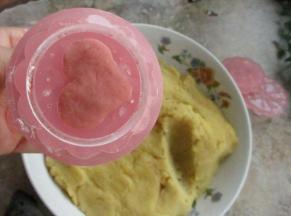 用月饼模具，选心形花片和玫瑰花花片。模具用熟的糯米粉撒一下防止粘连，先取一小块红色的绿豆泥，把心形的部分填满