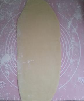 用擀面杖擀成长舌形。然后从上往下卷起。