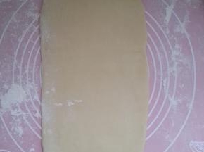 用擀面杖擀成长舌形。然后从上往下卷起。