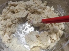 将披萨皮材料放入盆内，缓慢加入温水，用筷子不断搅拌成雪花状。