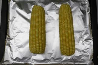 甜玉米去皮洗净，沥干水份，烤盘里垫上锡纸，玉米放在烤盘上