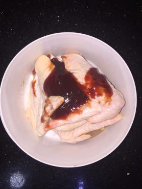 将鸡翅洗净控水后放入碗里，再放入3勺蜜汁烤肉酱