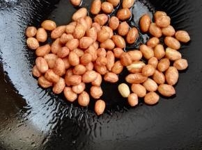 3、锅内倒入食用油，将花生下入锅中，小火慢煎。