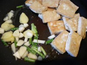 把豆腐推到一边，倒入葱姜蒜等调料。