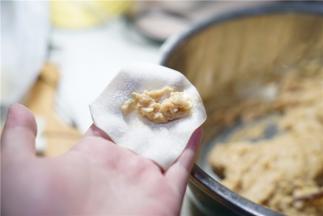 将调拌好的肉蓉包在馄饨皮里。